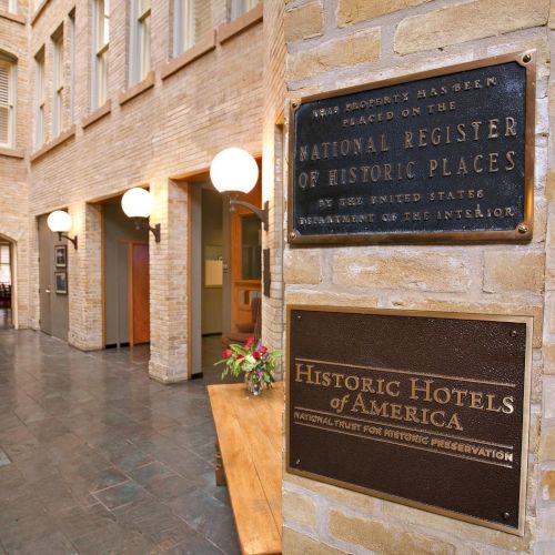A hotel lobby with vintage brick walls and plaques, including the National Register of Historic Places, and inviting seating inside.
